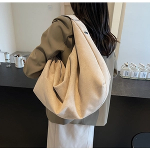 Side view of model wearing a large beige suede hobo bag with soft texture details