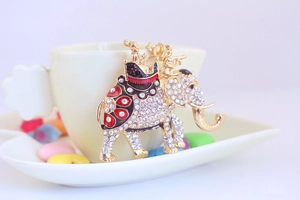 Macro shot of a gold elephant keychain with sparkling crystals leaning on a white ceramic cup