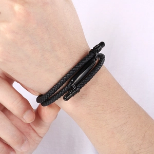 Detail of men's double-layered black braided leather bracelet on a wrist with metal clasp