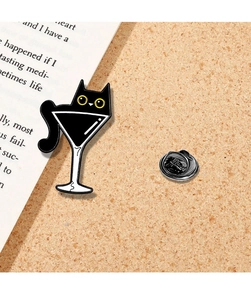 Close-up of cute black cat martini glass enamel pin on a warm cork board display