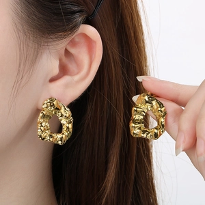 Detail view of model wearing gold irregular lava textured hollow circular earrings