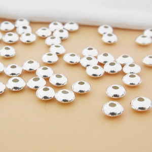 Vista macro de cuentas espaciadoras planas de plata esterlina S925 para joyería DIY
