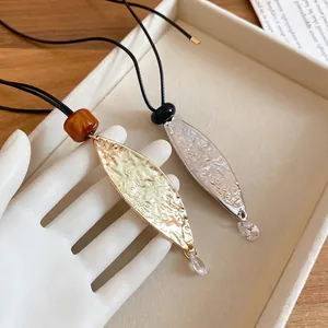 Minimalist leather leaf pendant necklace with hammered gold finish and crystal droplet