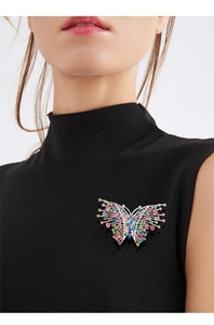 Detailed close-up of a vintage colorful rhinestone butterfly brooch on a black outfit