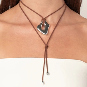 Close-up of brown suede cord necklace with irregular silver liquid metal pendant on neck