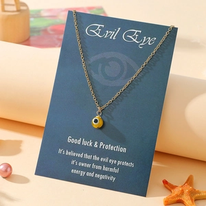 Detail of golden evil eye pendant necklace on a blue gift card with decorative starfish