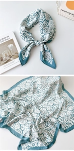 Detail of square silk scarf with blue rose patterns and border layout on display