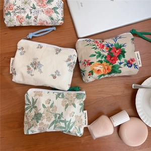 Close-up of four floral cotton mini pouches with zipper closure on a wooden desk