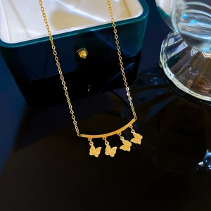 Detail of gold butterfly charms with matte texture on titanium steel necklace chain