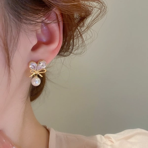 Close-up of zircon bow and pearl drop earring worn on model for a refined look
