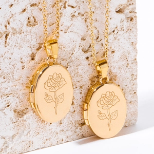 Oval gold locket necklace with rose engraving and O-chain on a stone background