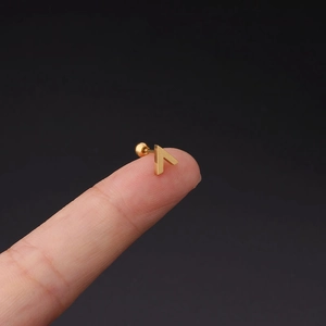 Close-up of a gold V-shaped stainless steel ear stud with ball screw back on fingertip