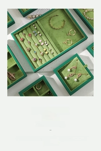 Macro view of green velvet jewelry display tray with specialized ring and necklace slots