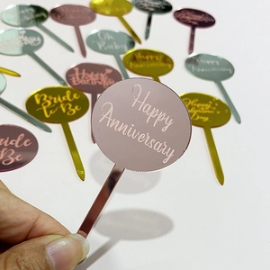 Primer plano de adorno acrílico para tartas en oro rosa con texto Happy Anniversary