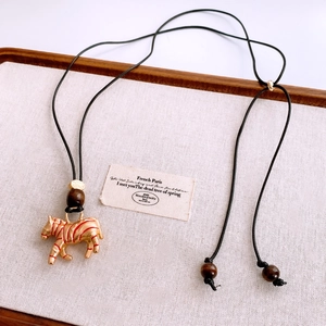 Close-up of zebra pendant necklace with red stripes, wood beads on a vintage tray