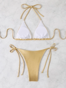 Flat lay of metallic gold bikini set with white halter cups and side-tie bottoms