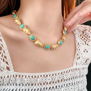 Gros plan d'un collier vintage doré avec pierres turquoise porté par un mannequin