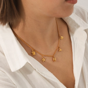 Golden ocean charm necklace with starfish shell and turtle pendants on model