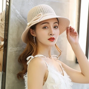 Detailed close-up of straw sun hat with elegant pearl and bow accent decorations