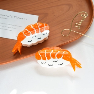 Detail shot of two creative sushi-shaped acetate hair claws on a wooden tray