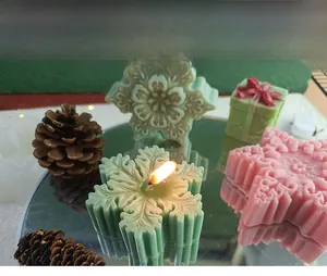 3D snowflake and gift box scented candles on a mirror tray with festive pine cones