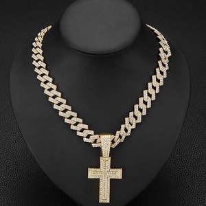 Détail du pendentif croix hip hop doré serti de cristaux sur un présentoir noir