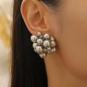 Close-up of silver geometric beaded cluster earrings on model ear with mirror finish