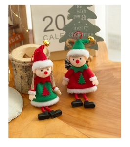 Close-up of cute Christmas elf dolls with golden bells and long legs on a wooden surface