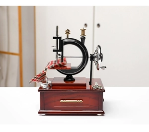 Detail of vintage sewing machine music box with wooden drawer and plaid fabric prop