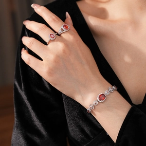 Detail of elegant silver bracelet and rings set with oval red zircons and fine diamonds