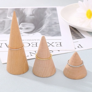 Three minimalist stackable rings in gold, silver, and rose gold on wooden display cones