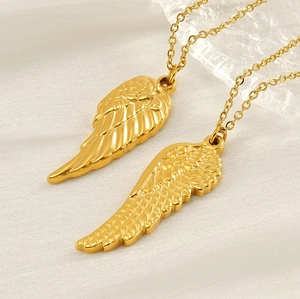 Close-up of golden angel wing pendants with rose engraving and feather texture details