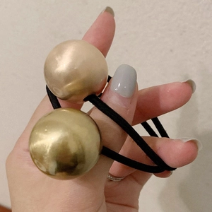Minimalist double gold beads hair tie on black elastic band shown in hand