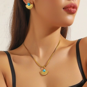 Close-up of gold-plated vintage sunburst necklace and earrings set with blue turquoise