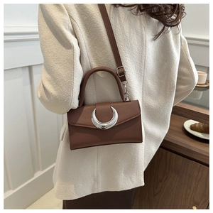 Détail du sac marron motif litchi avec boucle croissant argentée et bandoulière