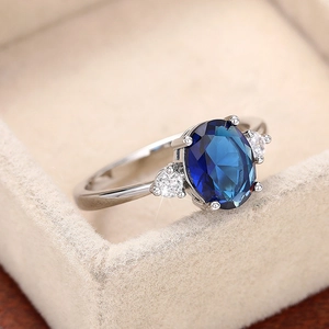 Dettaglio macro di un anello con gemma blu ovale e pietre bianche in una scatola