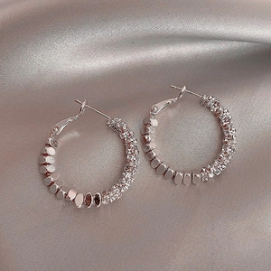 Macro view of vintage silver hoop earrings with zircon stones on silk fabric
