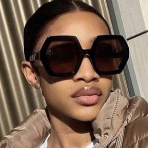 Stylish black oversized hexagonal sunglasses for women with dark lenses on a model