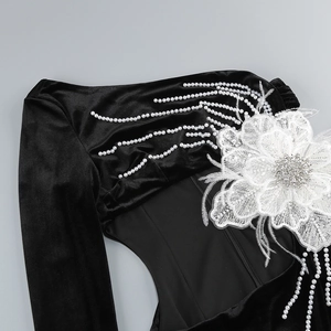 Détail d'une robe en velours noir avec fleurs en dentelle blanche et broderies de perles
