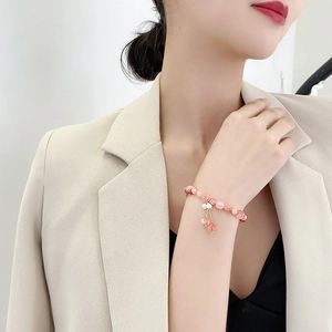Elegant pink crystal beaded bracelet with pearls and golden flower charms on model