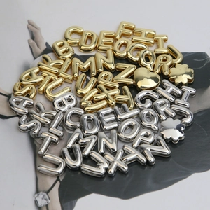Close-up of gold and silver metallic alphabet charms with glossy finish for bracelets