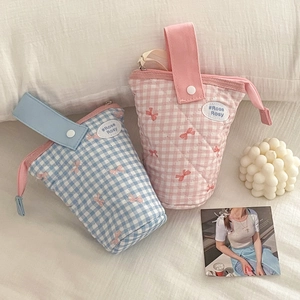 Quilted blue and pink makeup pouch with bow pattern and metal button strap on white fabric
