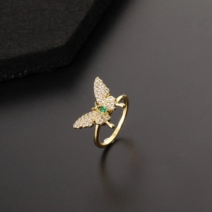 Detailed macro of gold butterfly ring featuring green marquise stone and zircon wings