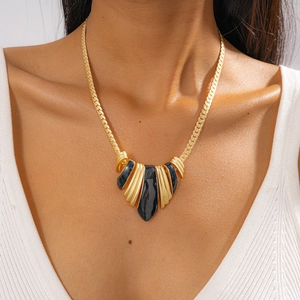 Detail of vintage gold braided necklace featuring black enamel geometric pendants on neck
