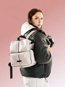 Gros plan du sac à dos matelassé beige avec texture rembourrée et détails zippés noirs