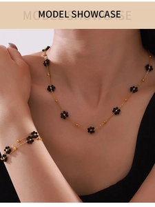 Détail du collier et bracelet dorés avec délicates perles de fleurs en pierre noire