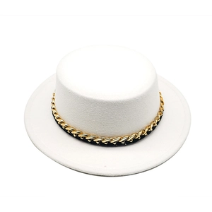 Detail of white boater hat featuring a gold chain link and black ribbon band decoration