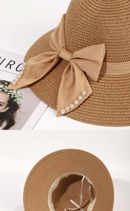Detailed close-up of straw sun hat with large bow and pearl accents in French style