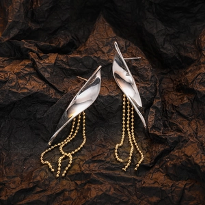 Silver willow leaf earrings with golden beaded chain tassels on textured background