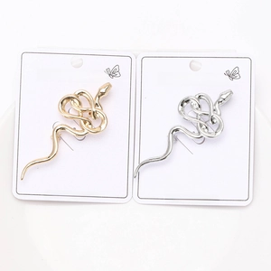 Detailed close-up of gold and silver snake-shaped brooches on display cards